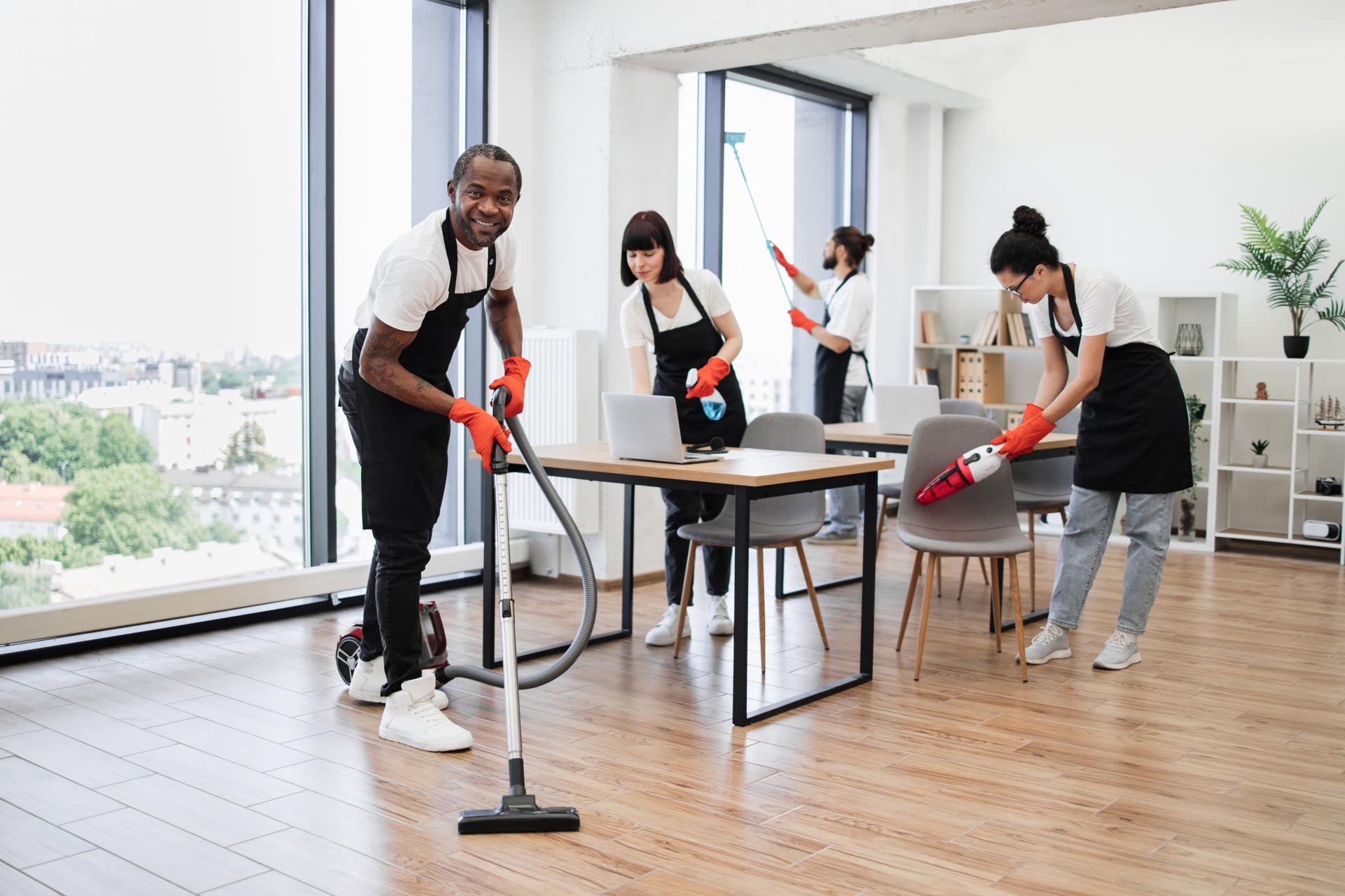 Side view of African American man using vacuum cleaner to clean floor from dirt.