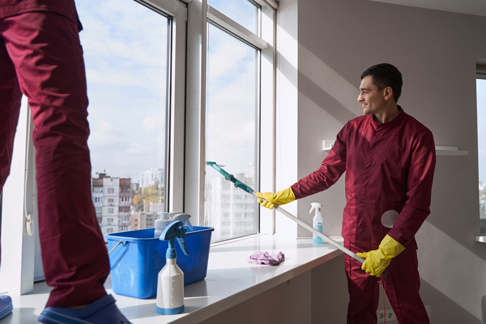 Experienced janitorial personnel in uniforms washing window